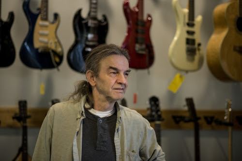 Danche Ivanovic in his shop in front of a wall of guitars
